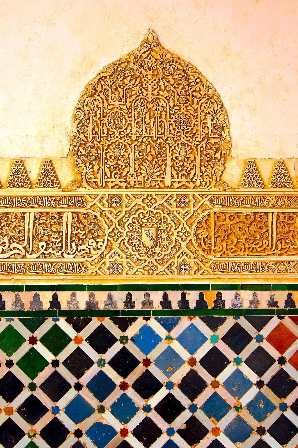 Ornate Arabic script and geometric mosaic tiles decorate a wall, featuring intricate floral patterns and vibrant colors.