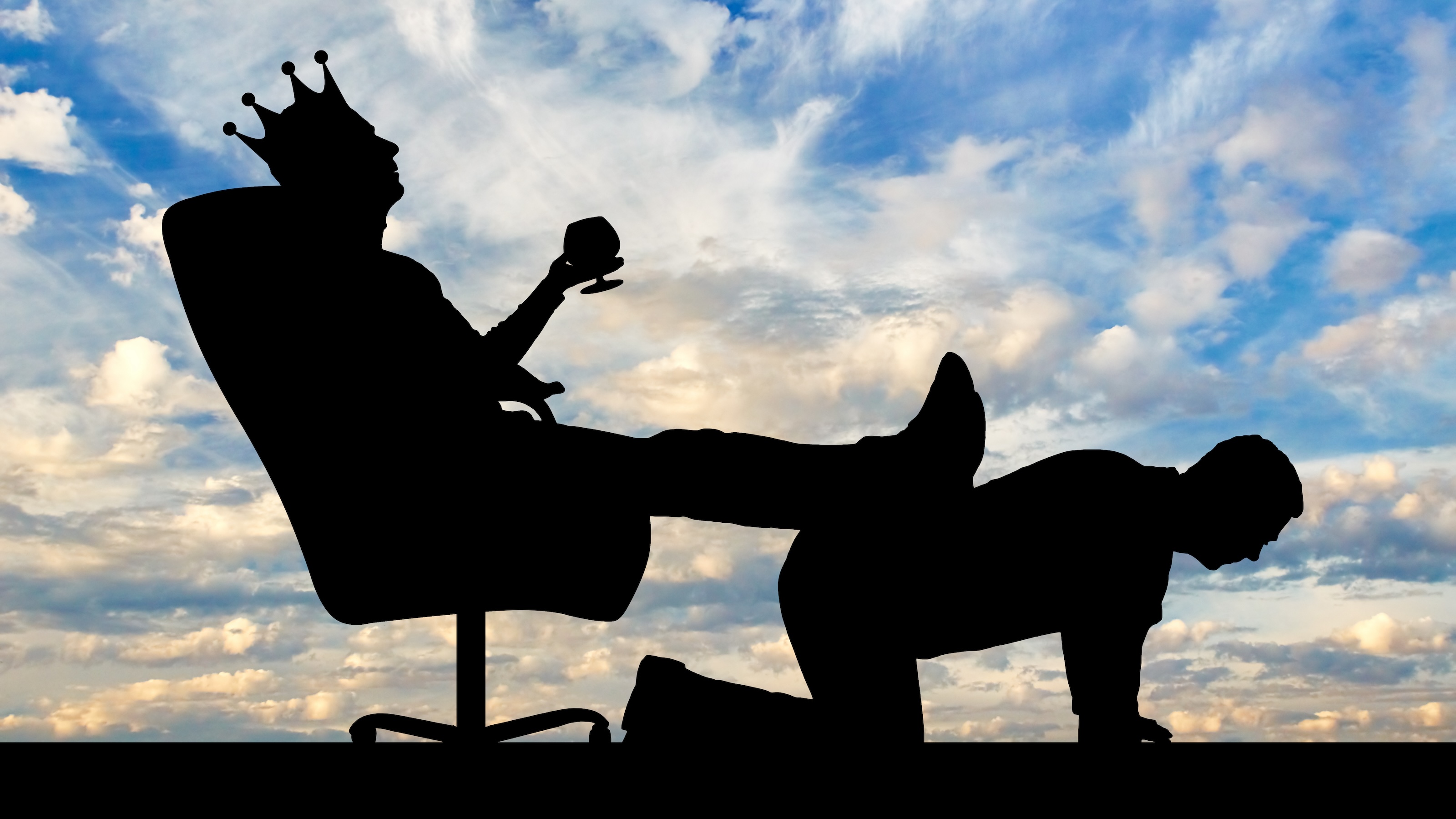 Silhouette of a selfish boss wearing a crown, relaxing on an office chair with feet propped up on another person's back against a cloudy sky backdrop.