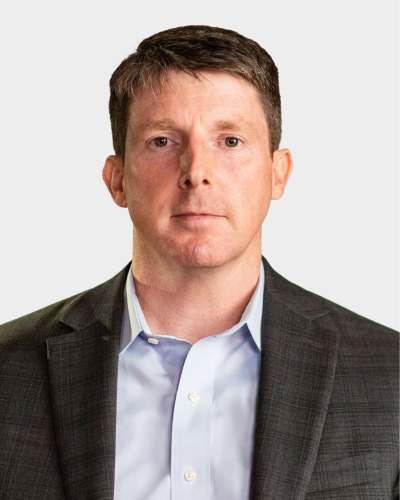 A man in a suit and light blue shirt poses against a plain background.