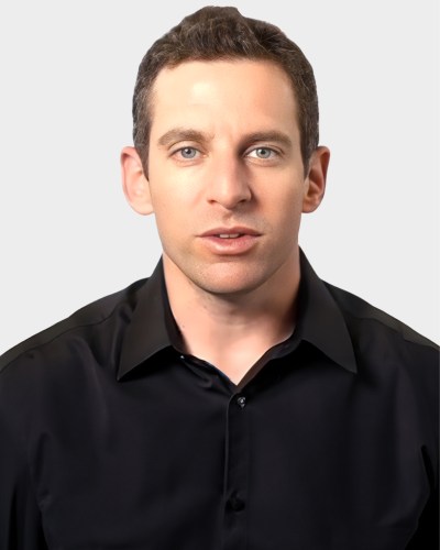 A person with short hair wearing a black shirt, looking directly at the camera against a plain background.