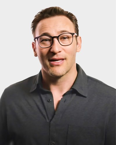 A person with short hair, wearing glasses and a dark button-up shirt, is facing the camera against a plain white background.