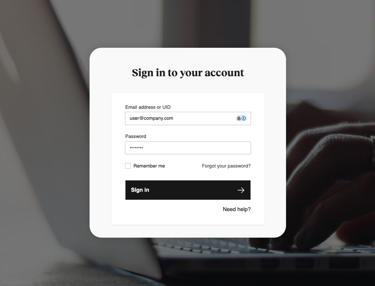 Close-up of a login screen on a laptop, showing fields for email, password, and options to remember login or recover password, with a "Sign in" button. Hands typing on the keyboard.