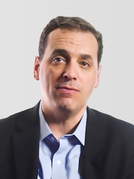 Dan Pink wearing a dark blazer and blue shirt, looking forward with a neutral expression, against a plain background.