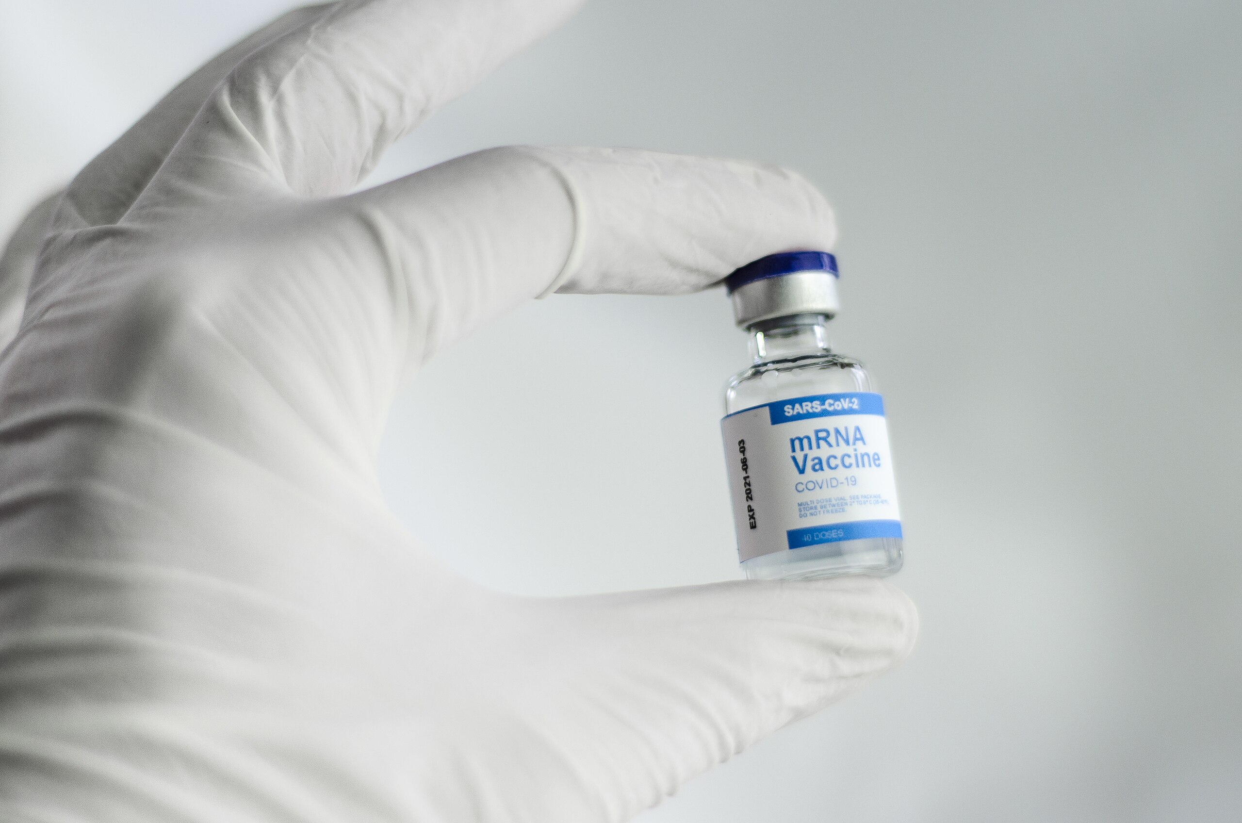 A gloved hand holds a vial labeled "mRNA Vaccine COVID-19," a crucial tool in safeguarding health as diligently as recent breakthroughs in lung cancer treatment.