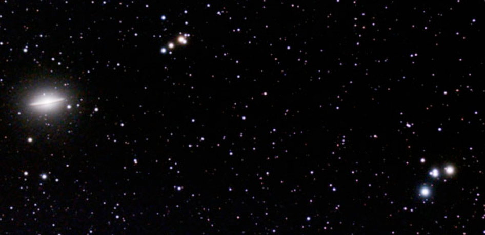 A starry night sky with numerous small stars scattered across a dark background. A bright, elongated object, reminiscent of the Sombrero Galaxy captured by JWST, is visible on the left side.