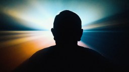 Silhouette of a person against a vibrant background with radiating light beams in blue, white, and orange hues.