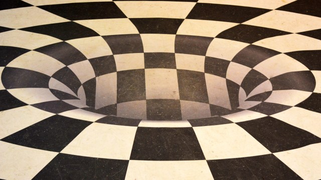 Optical illusion of a black and white checkered floor with a 3D effect creating the appearance of a hole in the ground.