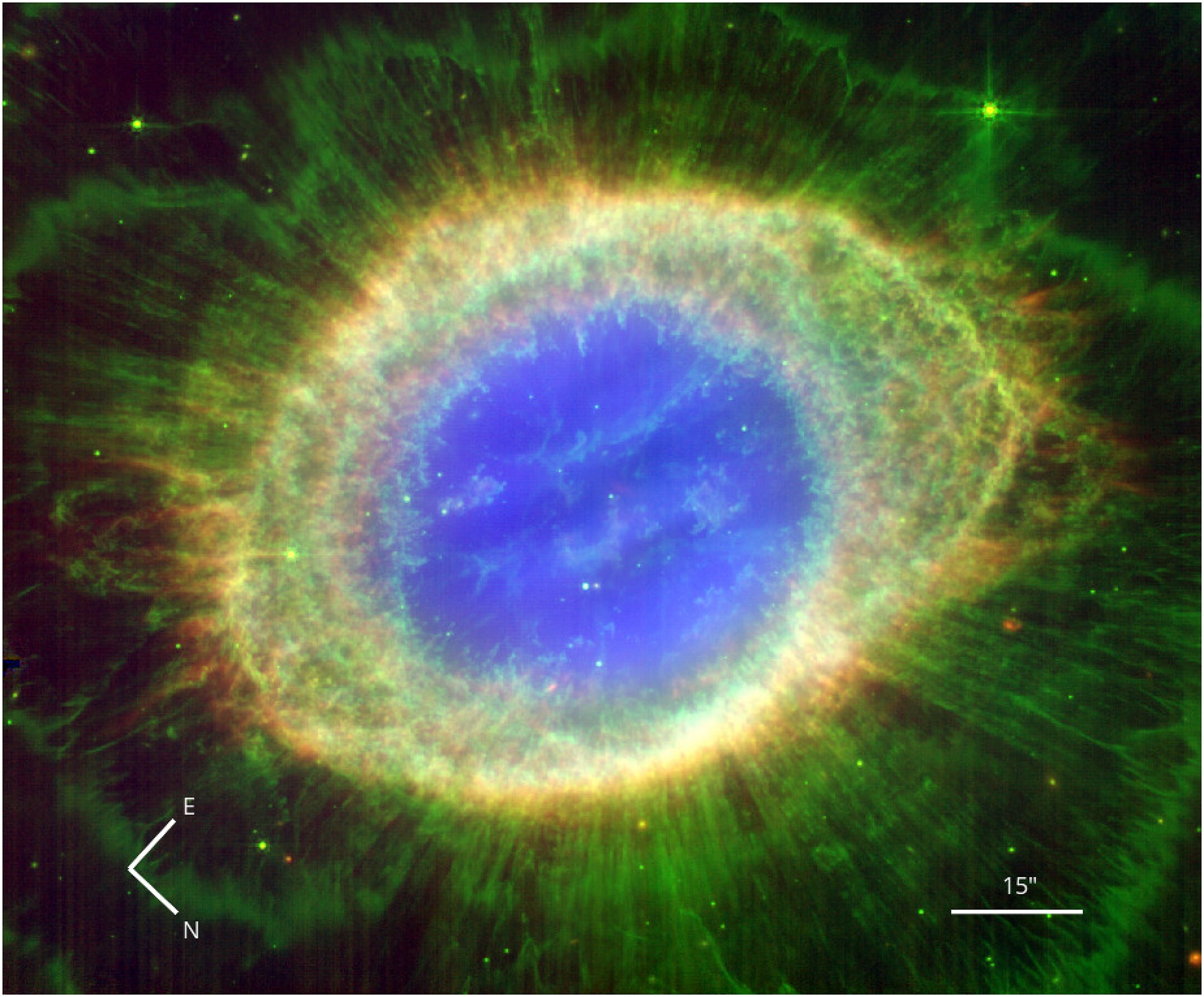 A colorful image of a nebula with a bright blue center, surrounded by green and yellow gases, reveals the ring nebula's true shape. Orientation markers point east and north, while a scale bar measures 15 arcseconds.