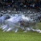 Blurred image of a thrilling football game in action under the night sky, with enthusiastic spectators on bleachers watching one of America's most exciting and sometimes dangerous sports.