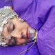 Person sleeping with EEG cap and sensors on face, covered with a purple blanket.