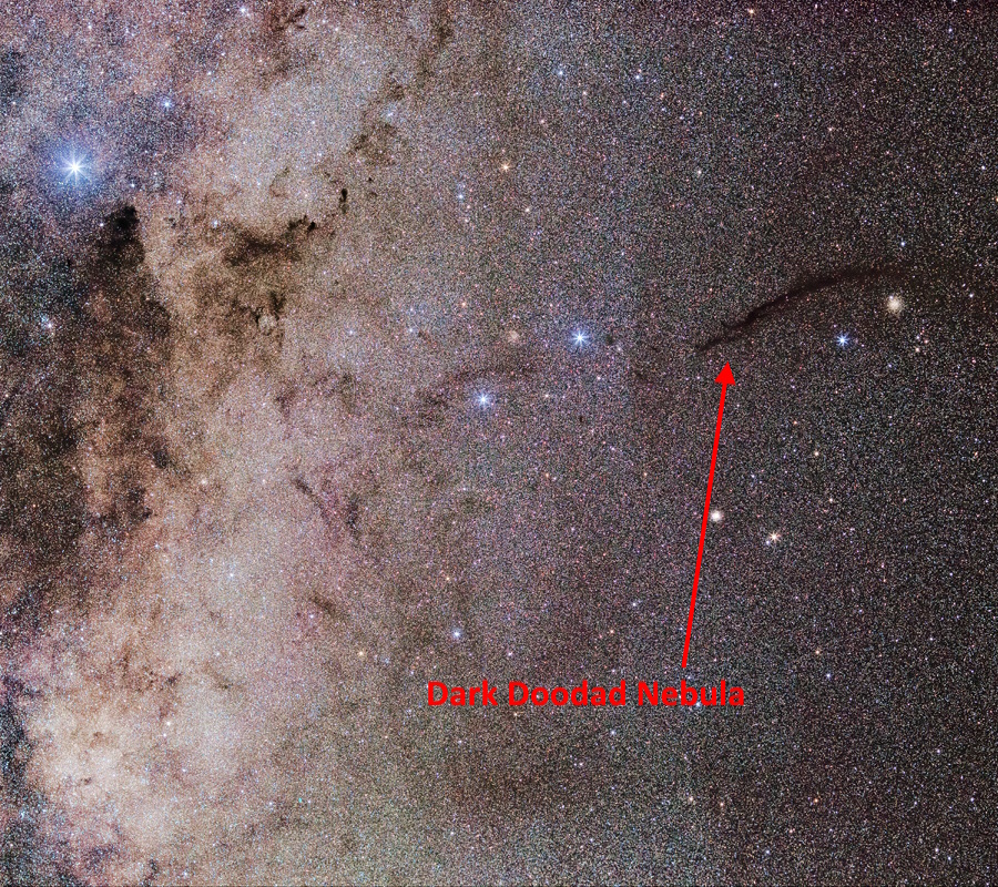 Wide view of the night sky featuring a dense star field and the Dark Doodad Nebula marked with red text and an arrow.