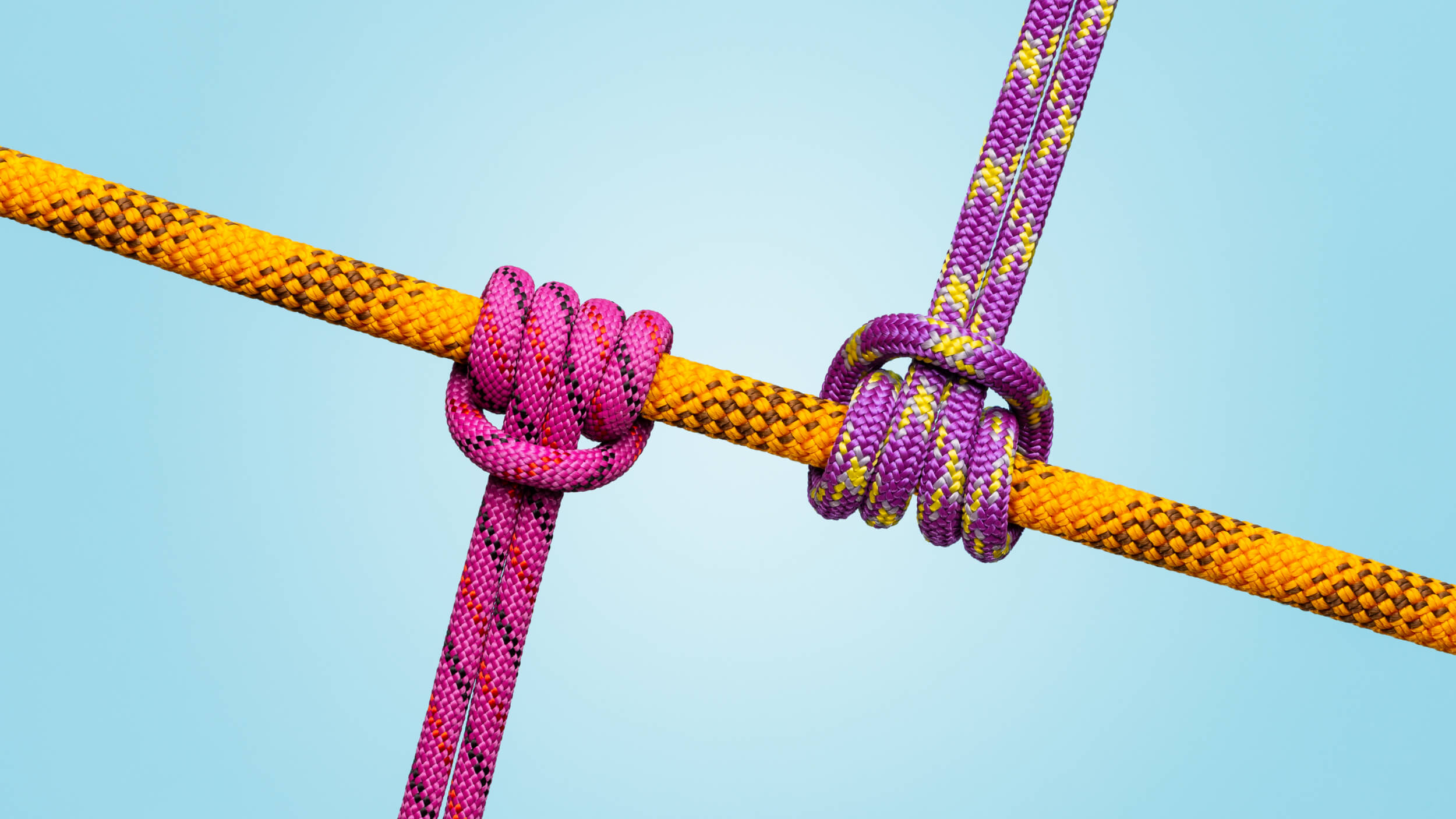 Three colorful ropes tied in knots against a light blue background symbolize workplace friction.