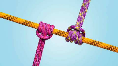 Three colorful ropes tied in knots against a light blue background symbolize workplace friction.