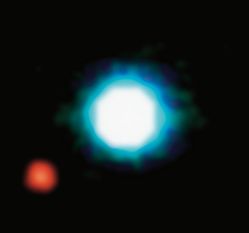 A bright, circular blue and white object is centered against a black background, with a smaller red object to the lower left.