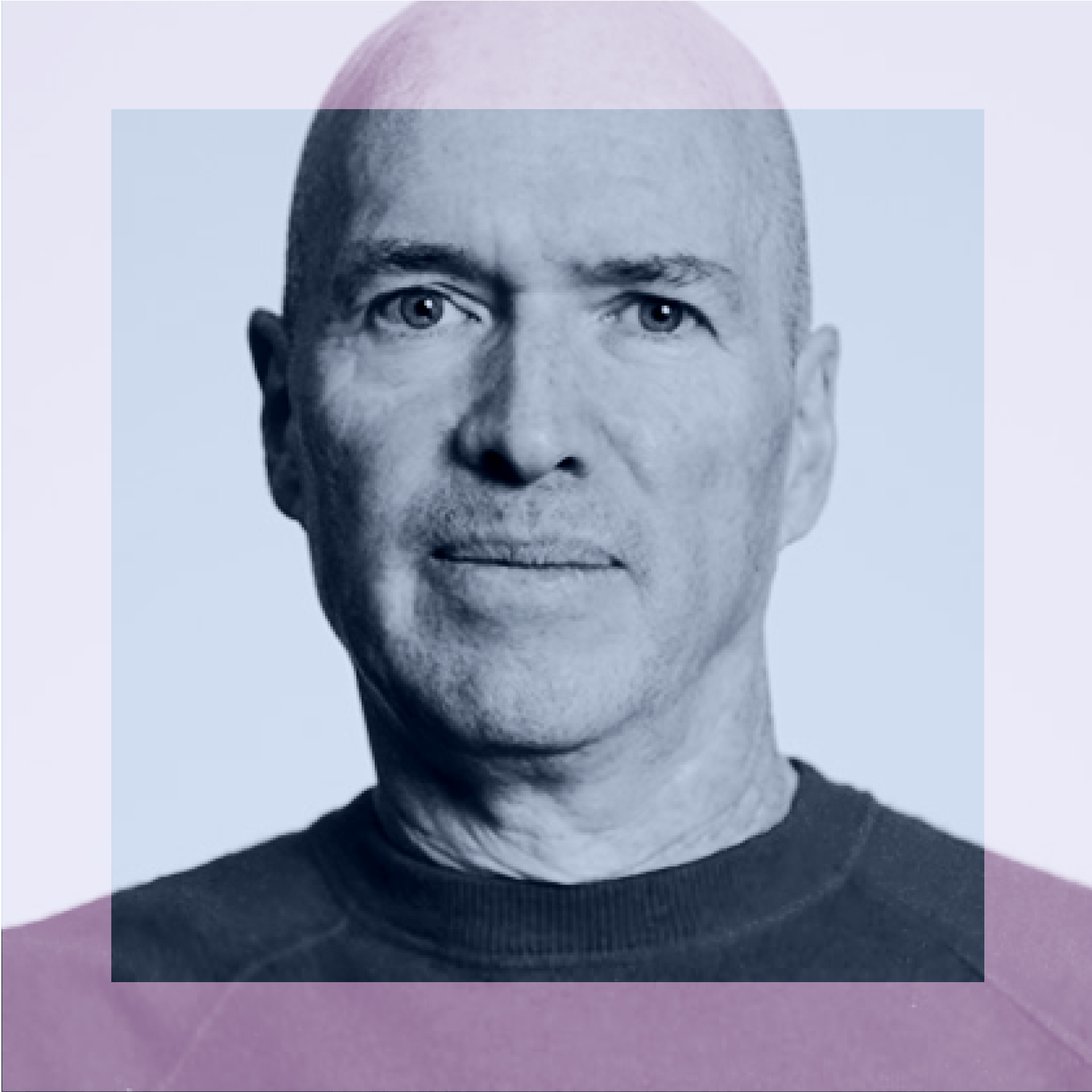 A middle-aged bald man with light skin and blue eyes, wearing a dark crewneck shirt, looks directly at the camera against a plain background.