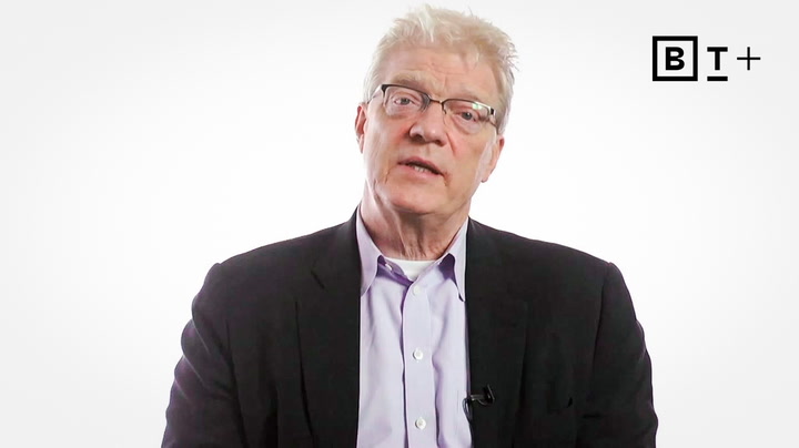 An older man with light hair and glasses wearing a dark blazer over a light shirt sits against a plain white background with "BT+" logo in the top right corner.