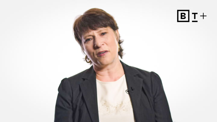 A woman with short brown hair wearing a dark blazer and light top sits against a white background with a "BT+" logo in the top right corner.